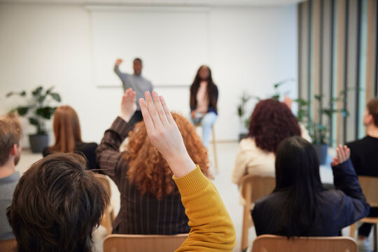 Corporate colleagues raising hands during meeting in office