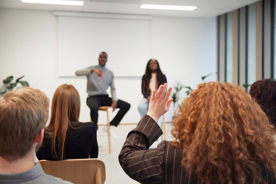Businesswoman raising hand during discussion in office