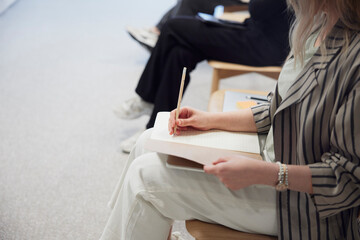 Midsection of young businesswoman writing on note pad during meeting in office