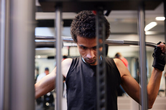 Focused young man doing lateral pull-down weightlifting at gym