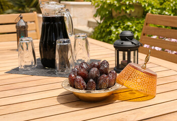 plate of fresh dates next to tamarind juice on a wooden table in the home garden