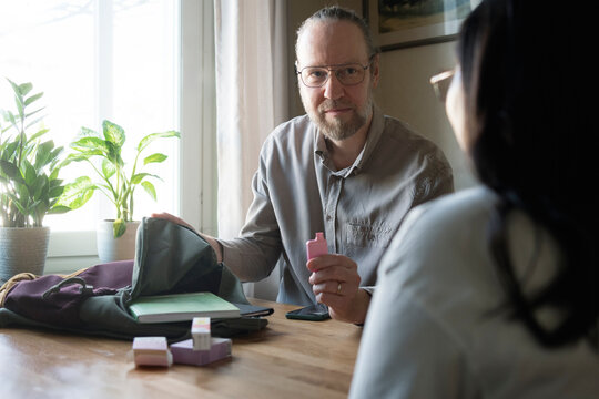 Father removing electronic cigarette from daughter's bag at home