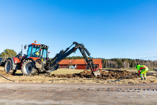 Maintenance engineer removing dirt with backhoe from ground on sunny day