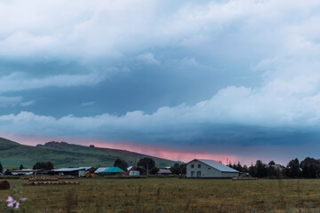 The red sunset shines through between the mountains and dark clouds.