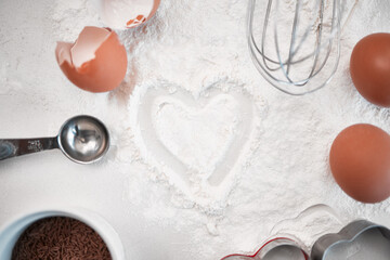 Flour, eggs and heart on table for baking, cake and dessert in France with top view, spoon and...