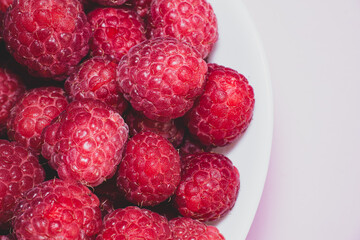 Close up shot of fresh ripe red raspberries in a white plate