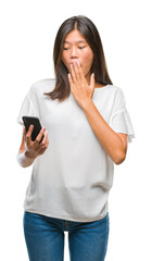 Young asian woman texting using smartphone over isolated background cover mouth with hand shocked with shame for mistake, expression of fear, scared in silence, secret concept