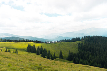 Obraz premium beautiful landscape in the mountains silhouettes of peaks, forest, trees, travel, in green tones, polonyna, Carpathian, blue clouds, green grass, hiking in the mountains, poster, wallpaper, house 