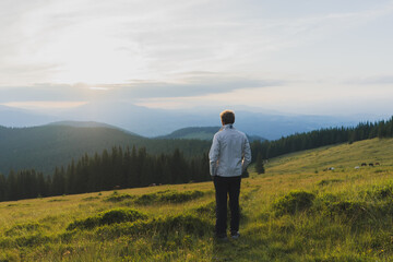 man on a hill overlooking a mountain range, against the background of mountains, tourism, hiking, time together, family, relationships, nature of the Carpathian, vacation, outdoor activities, meditati