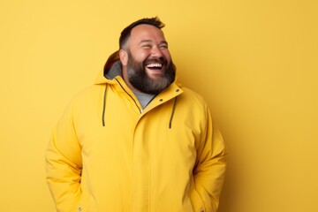 Obraz premium Portrait of a joyful man in his 40s wearing a warm parka on pastel yellow background