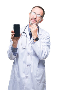 Middle age senior hoary doctor man showing smartphone screen over isolated background serious face thinking about question, very confused idea