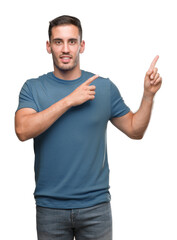 Handsome young casual man smiling and looking at the camera pointing with two hands and fingers to the side.