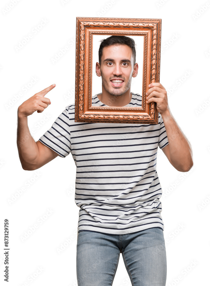 Poster Handsome young man looking through vintage art frame very happy pointing with hand and finger