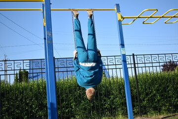 A young man in athletic wear performs morning workout routine at an outdoor gym. He trains...