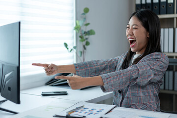 A woman is pointing at something on a computer screen and laughing