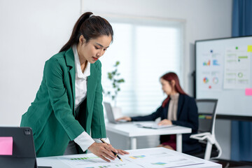 A woman in a green jacket is looking at a piece of paper
