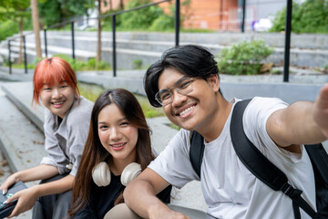 Three young people are sitting on a ledge, smiling and posing for a picture