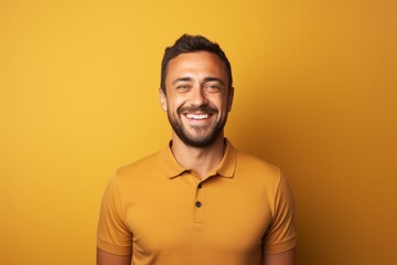 Obraz premium Portrait of a cheerful man in his 30s wearing a sporty polo shirt in front of pastel brown background