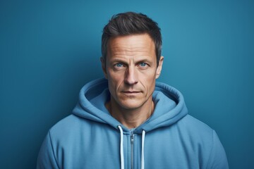 Fototapeta premium Portrait of a content man in his 40s wearing a zip-up fleece hoodie isolated on soft blue background
