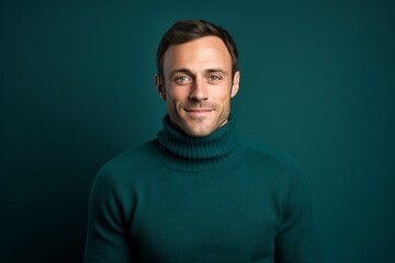 Fototapeta premium Portrait of a satisfied man in his 30s wearing a classic turtleneck sweater isolated on soft teal background