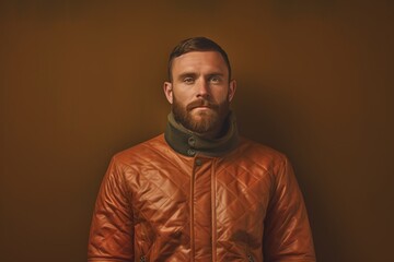 Obraz premium Portrait of a glad man in his 30s sporting a quilted insulated jacket on soft brown background