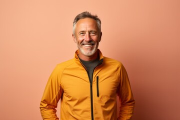 Fototapeta premium Portrait of a cheerful man in his 60s sporting a technical climbing shirt in soft brown background