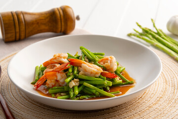 Stir fry asparagus and shrimp with garlic in oyster sauce in white plate.