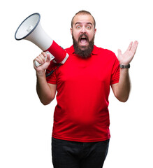 Young caucasian man shouting through megaphone over isolated background very happy and excited, winner expression celebrating victory screaming with big smile and raised hands