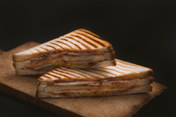club sandwich on a wooden board on a dark background