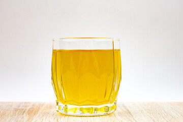 Yellow drink in a glass. A glass with yellow-orange liquid, green tea.