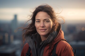Portrait of a blissful woman in her 30s donning a durable down jacket isolated in modern cityscape background