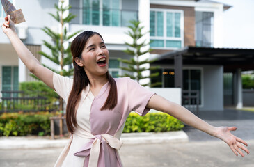 Portrait of happy attractive Asian women holding a lot of banknotes in front of home to celebrate and Pay the final installment of the house, Loans for real estate concept, Smiling young successful