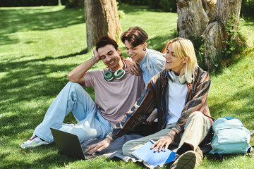 Three young queer friends laugh together in a park on a sunny day.