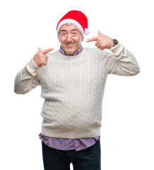 Handsome senior man wearing christmas hat over isolated background smiling confident showing and pointing with fingers teeth and mouth. Health concept.