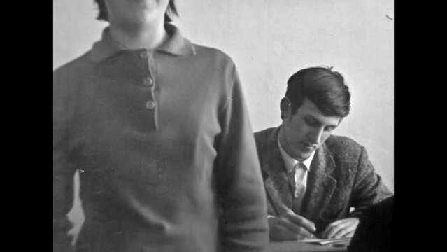 Archive film, woman professor teacher teaching lesson to students in university classroom. Student writing, learning lecture in college indoor. Study at lecture. Vintage black white movie. Retro 1980s