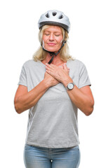 Middle age caucasian cyclist woman wearing safety helmet over isolated background smiling with hands on chest with closed eyes and grateful gesture on face. Health concept.