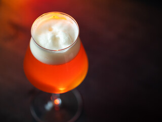 A glass of beer on a wooden table in a teku glass, copy space top view