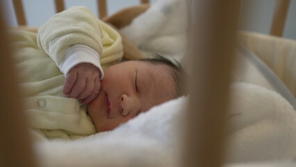 Adorable newborn baby in a yellow onesie peacefully asleep in a wooden crib, capturing the tranquility and purity of early childhood, ideal for family and healthcare