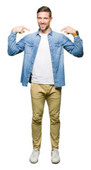 Handsome man with blue eyes and beard wearing denim jacket looking confident with smile on face, pointing oneself with fingers proud and happy.