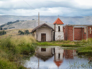 Templo antiguo cristiano de arquitectura de adobe y su reflejo en el agua, de fondo las montañas en un día nublado. Ubicado en Vacas, Cochabamba - Bolivia