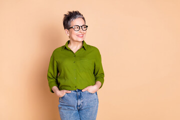 Photo portrait of lovely pensioner lady look empty space hands pockets dressed stylish green...