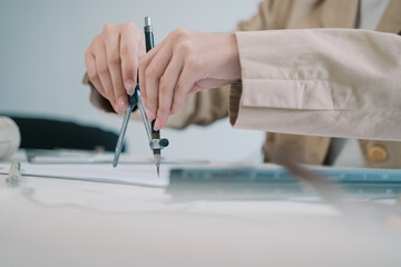 In her office, the professional woman architect meticulously uses a compass in hand to refine the...