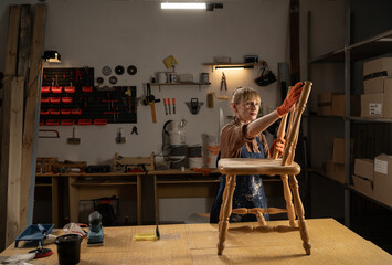 Furniture restoration craftsman sanding old chair owning manufacturing business serious woman craftsman repairing furniture using equipment and tools at work place