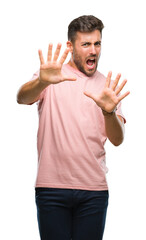Fototapeta premium Young handsome man over isolated background afraid and terrified with fear expression stop gesture with hands, shouting in shock. Panic concept.