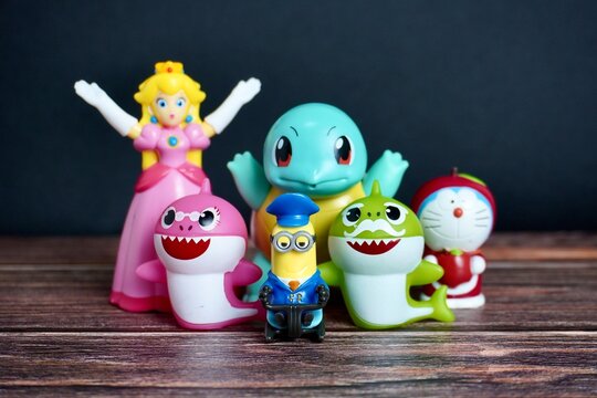 Jakarta, Indonesia - July 3rd, 2024 - Groups of children or kids toys figure object from mario bros, baby shark, despicable me, pokemon, and doraemon isolated on dark wooden surface background.