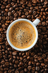 Fototapeta premium Cup of freshly brewed coffee placed on a bed of roasted coffee beans, highlighting the rich aroma and flavor of the beverage.