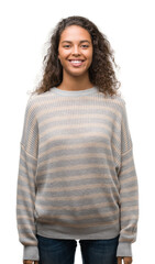 Beautiful young hispanic woman wearing stripes sweater with a happy and cool smile on face. Lucky person.