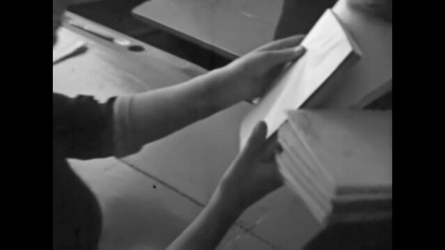 Teacher collects students homework in classroom. Pupils sit at desks, gave exam test to professor in college. Secondary school education. Vintage black white film. Retro 1980s archive. Student study