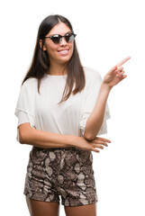 Young beautiful hispanic wearing sunglasses very happy pointing with hand and finger to the side