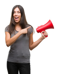 Young hispanic woman holding megaphone very happy pointing with hand and finger